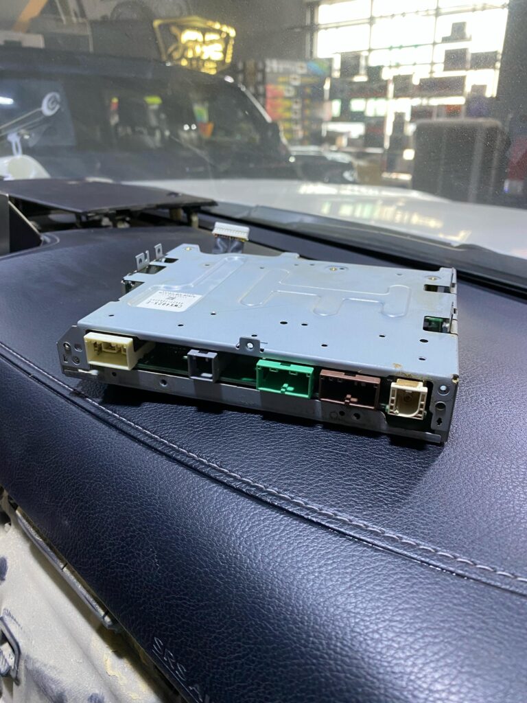 Connector side of the AVN ECU from a Lexus LX570, showing LVDS, optical fiber, and power/data ports used for multimedia system integration