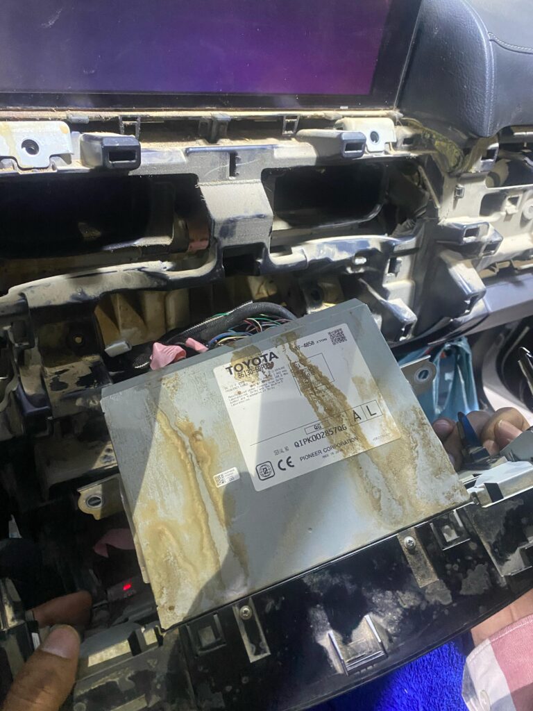 Close-up of partially removed Mark Levinson head unit in a Lexus LX570, showing signs of water damage before AVN ECU replacement