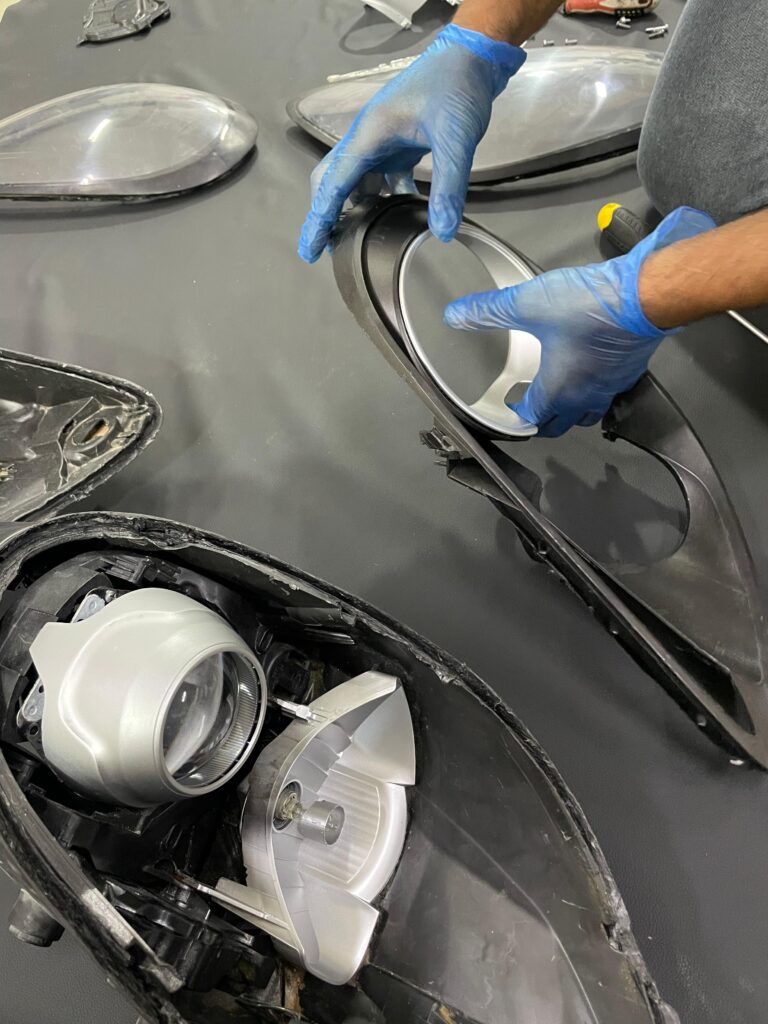 Technician assembling headlight components of a 2014 Porsche Cayman during a retrofit service at DSUS Auto Care Center in Dubai
